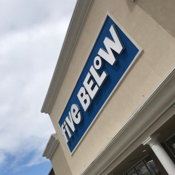 Five Below - The image shows a Five Below storefront sign attached to the exterior wall of a shopping center, with part of the building and a person visible. - Discount Store Near Me - Lexington, Kentucky