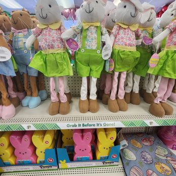 Dollar Tree - The image shows a variety of plush bunny and mouse toys arranged on store shelves. The toys are dressed in colorful outfits, including floral shirts, green skirts, and yellow bow ties. Some of the plush toys are holding Easter-themed decorations, such as eggs and bunny-shaped containers. The display is part of a seasonal or holiday-themed section, with a sign that says "Grab It Before It's Gone!" and other Easter-related items visible below the toys. - Discount Store Near Me - Pompano Beach, Florida