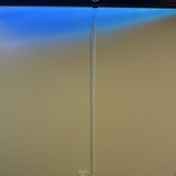 24K CCTV - Bedroom TV wire case cover - A television displaying streaming service icons is mounted on a beige wall, with a visible power cable running down to an outlet. - Security Systems Near Me