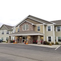 Vista Prairie at Copperleaf - The exterior of the multi-story building featuring sage green siding, stone pillars, and white shutters...