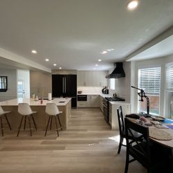 An open kitchen concept layout with kitchen counter seating, new appliances, flooring, and kitchen cabinets.