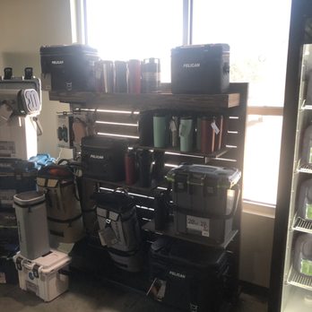 HTeaO - Pelican products. - Pelican brand coolers and drinkware are arranged on a black metal shelf near a window, with additional products on a nearby refrigerated shelf. - Coffee & Tea Near Me - Georgetown, Texas