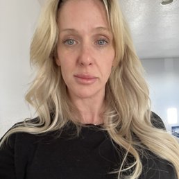 No bruising at all. - A woman with long, wavy blonde hair and blue eyes poses for a selfie in an indoor setting with neutral-colored walls.