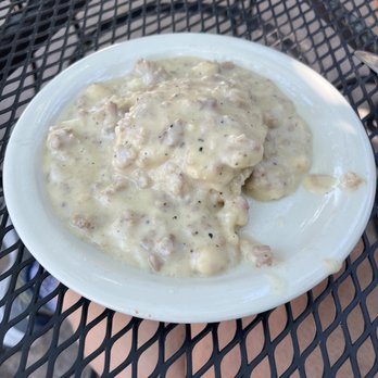 Kate's Place - Biscuit and gravy - A white plate holds biscuits covered in creamy gravy, placed on a black metal outdoor table. - American Near Me - Ridgway, Colorado