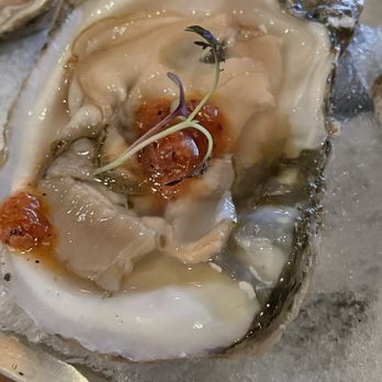 3128 Social House - Raw oysters - A close-up of a raw oyster served on ice, with a dollop of sauce and microgreens on top. The oyster shell is partially visible, and the presentation emphasizes freshness and seafood quality. - Gastropubs Near Me - Albuquerque, New Mexico