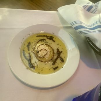 Surfside - Oil for bread! - A white plate contains a spiral-shaped food item, surrounded by olive oil and drizzled with balsamic vinegar, on a white tablecloth. - Seafood Near Me - Montauk, New York