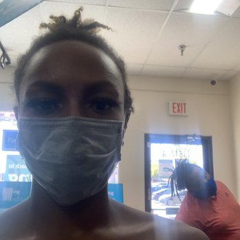 The UPS Store - A person wearing a face mask is taking a selfie inside a store, with a second person in the background near the entrance. - Shipping Centers Near Me - Silver Spring, Maryland