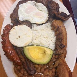 White rice, beans, eggs, steak, chorizo, chicken, platano maduro, avocado, and a small arepa.