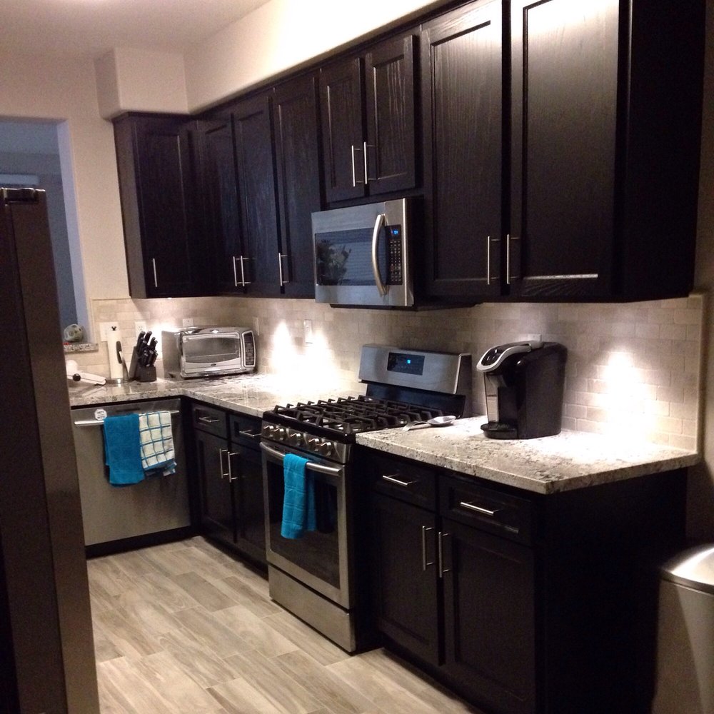 Phoenix Stone - a kitchen with black cabinets and stainless steel appliances - General Contractors Near Me - San Jacinto, California Phoenix Stone - a kitchen with black cabinets and stainless steel appliances - General Contractors Near Me - San Jacinto, California