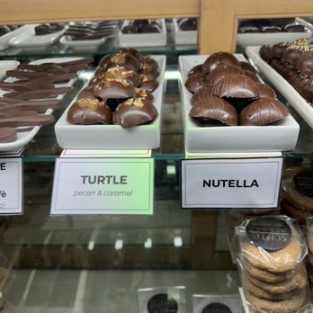 Scialo Bros. Bakery - Delicious treats! - Chocolate candies labeled 'Turtle' with pecan and caramel, and 'Nutella' are displayed in white trays inside a bakery case. - Bakeries Near Me - Providence, Rhode Island