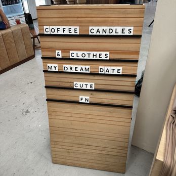 Forth & Nomad - A wooden letter board with black lines shows a message about coffee, candles, clothes, and a date, in a retail or cafe setting. - Accessories Near Me - Houston, Texas