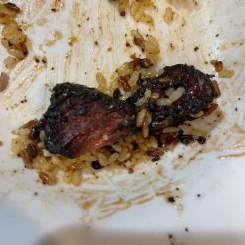 Denny's - Skillet "Brisket" ( burnket) - The image shows burnt bacon pieces and rice remnants on a white plate, with some bread pieces at the top. - Diners Near Me - Oneonta, New York