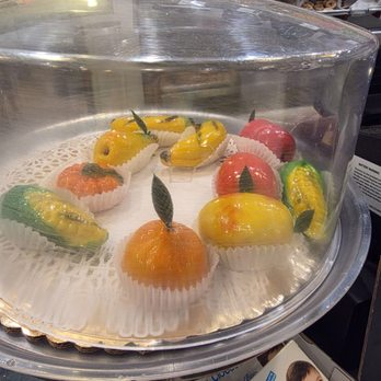 Modern Pastry Shop - Fruit pastry - Assorted fruit-shaped pastries are arranged on a tray inside a glass display case at a bakery, with some in paper cups and decorative leaves. - Bakeries Near Me - Boston, Massachusetts