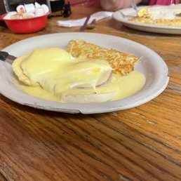 a plate of eggs benedict with a side of hash browns a plate of eggs benedict with a side of hash browns