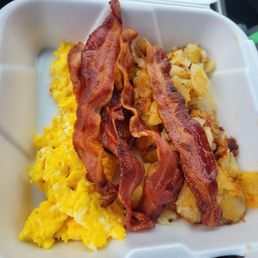 A 3 egg breakfast, breakfast potatoes, and 4 slices of bacon, with toast not seen.