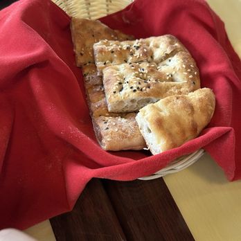 Efesus Cafe - bread basket - A basket containing various types of bread, including flatbread and pita, lined with a red cloth, placed on a table. - Mediterranean Near Me - Ashburn, Virginia