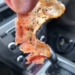 a hand holding a piece of bacon a hand holding a piece of bacon