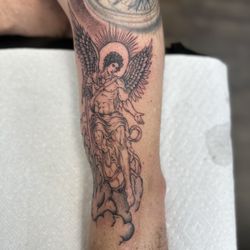 Black and grey Archangel Michael tattoo featuring detailed wings, clouds, and religious imagery, custom realism tattoo by Britt at Crooked S