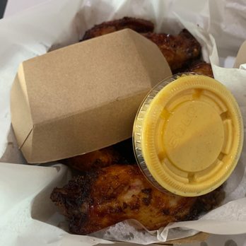 Fat Dan's - Fried chicken pieces with a yellow dipping sauce in a plastic cup, served in a paper-lined basket with a cardboard container. - Delis Near Me - Indianapolis, Indiana