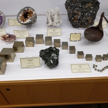 Mineralogical Museum - Mineral specimens and metal cubes are arranged on a white display table at the Mineralogical Museum in Socorro, NM, with labels identifying each mineral. - Museums Near Me - Socorro, New Mexico
