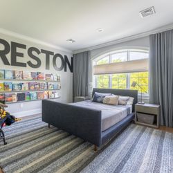 Budget Blinds of North Greensboro - Custom woven wood Roman shades paired with floor-to-ceiling gray drapery panels.