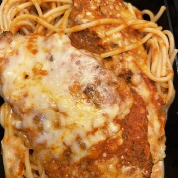 Olivadi - The image shows a serving of spaghetti pasta with marinara sauce, topped with melted cheese and two meatballs. The pasta is intertwined with the sauce, and the cheese appears bubbly and slightly browned. The dish is presented in a black container, highlighting the Italian-inspired meal. - Italian Near Me - Norwood, Massachusetts