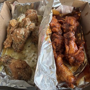 Wingnutz - The image shows a takeout box with two sections of fried chicken. The left section contains breaded chicken pieces sprinkled with seasoning, while the right section has chicken coated in a dark, glossy sauce. The box is lined with foil and placed on a patterned surface, with some food remnants visible. - Chicken Wings Near Me - Buffalo, New York