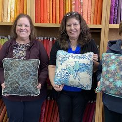 Students proudly display their finished custom throw pillows after a Decorative Stitch class...