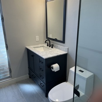 Second Mile Tile - a bathroom with a toilet, sink, and mirror - General Contractors Near Me Second Mile Tile - a bathroom with a toilet, sink, and mirror - General Contractors Near Me