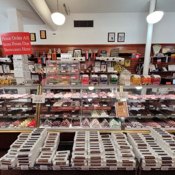 Granite State Candy Shoppe - So many sweets - A candy shop interior with shelves of chocolates, candies, and treats, including a glass display case and a sign for ordering items. - Candy Stores Near Me - Concord, New Hampshire