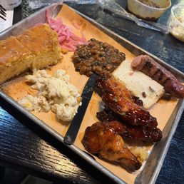 Clockwise from top left: pickled onions, baked beans, Cajun sausage, peach tea smoked chicken wings, Mac & cheese, sweet potato cornbread