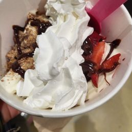 a hand holding a bowl of ice cream and strawberries a hand holding a bowl of ice cream and strawberries