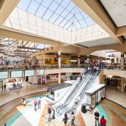 Superstition Springs Center - Shoppers use the center court escalators beneath a large skylight at Superstition Springs Center.