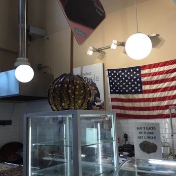 Kilwins Ice Cream - Chocolate - Fudge - Caramel apple on a stick with the U.S.A flag in the background. - Desserts Near Me - Alexandria, Virginia