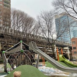 Coliseum Park - Climbing structure, two slides, hills, and a passing L-train on the green or orange line. The orange posts are the saucer swing.