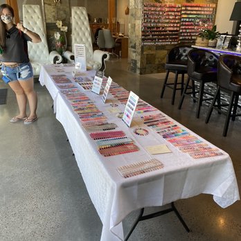 Nails Uncorked Amazon - Huge nail polish selection - A long table covered with a white cloth showcases numerous nail polish color samples and color charts in a salon environment. - Nail Salons Near Me - Eugene, Oregon