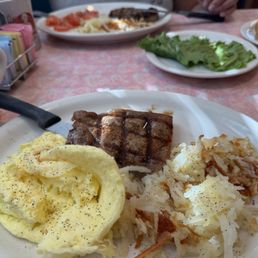 American Classic T-Bone Steak and Eggs, with a side of tomatoes.