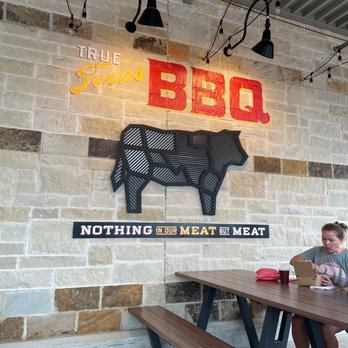 True Texas BBQ - a man sitting at a picnic table - Barbeque Near Me - New Braunfels, Texas