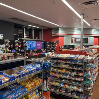 QuikTrip - The image shows the interior of a convenience store with snack shelves stocked with various packaged snacks, including cookies and chips. Beverage dispensers are visible in the background, along with a digital screen displaying a message. The store has a red and gray color scheme, with a tiled floor and ceiling lighting. An ATM sign is seen in the upper right corner, indicating additional services available. - Gas Stations Near Me - Lindale, Texas