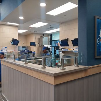 Culver's - Inside a fast-food restaurant, staff in blue uniforms work behind the counter with multiple screens and equipment. - Fast Food Near Me - Chicago, Illinois