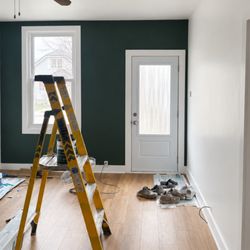 Enviro Painting - A freshly-painted interior entryway featuring modern colors and a bold, dark green accent wall.