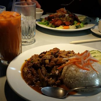 Cafe Da Lat - Crispy quail at the back, drinks, pork & eggplant up front. - A plate of rice with vegetables and meat, a glass of iced coffee, and water on a restaurant table. - Vietnamese Near Me - Albuquerque, New Mexico