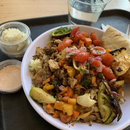 Grains and greens bowl with chicken, roasted veggies, and tomato onion salad.