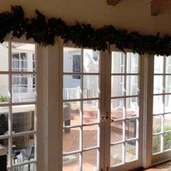 House Stars Holiday Lighting Installation - Decoration of interior home with green garlands and lights along interior windows.