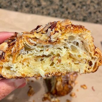 Camina Bakery - a hand holding a half eaten pastry - Bakeries Near Me