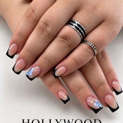 Black French tips with blue floral accents by Hollywood Nails & Spa.