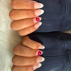 Naveana Nail Salon - Glossy almond French tips with delicate pink-red floral accents and tiny gold centers.