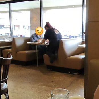 Elly's Pancake House - Not sure if she was tired or she always rest in the booth with customers - A woman with red hair is leaning over a table to talk to a person seated in a booth at a restaurant with large windows. - Breakfast & Brunch Near Me - Norridge, Illinois