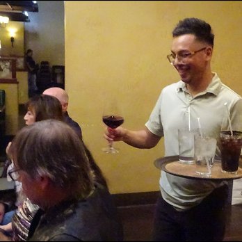 Table 59 - Our friendly host serves one of our guests a glass of red wine, as he has Pepsi and ice water to deliver to others. - Italian Near Me - Merced, California
