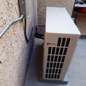 Clark & Sons Aire - Outdoor Heat Pump installed on an AC pad on a condo patio. - Heating & Air Conditioning/HVAC Near Me Clark & Sons Aire - Outdoor Heat Pump installed on an AC pad on a condo patio. - Heating & Air Conditioning/HVAC Near Me